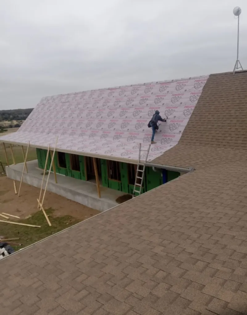 Worker preparing underlayment for a metal roof installation in Norwood